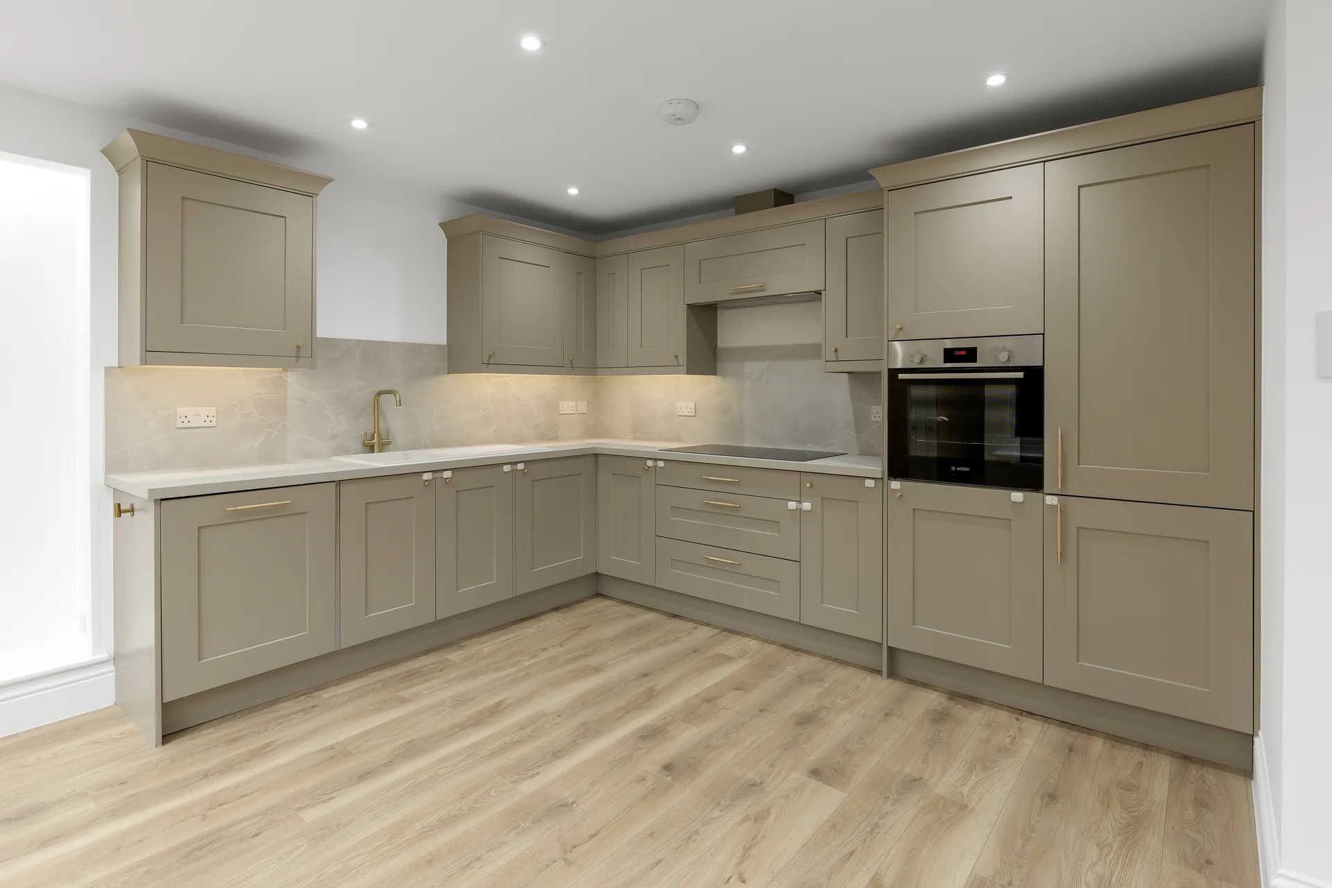 Clean, Empty Modern Kitchen With Light Olive Green Shaker Style Cabinets And Light Wood Flooring.